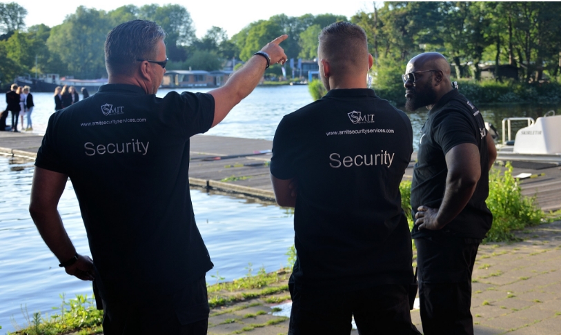 Drie beveiligers van Smit Security Services houden wacht, één beveiliger wijst